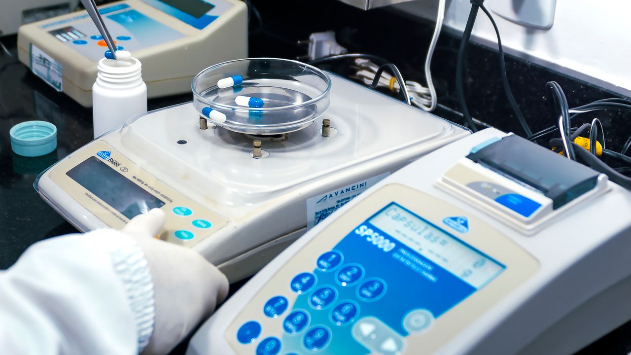 Menu Close-up of laboratory equipment with capsules, capturing pharmaceutical analysis.