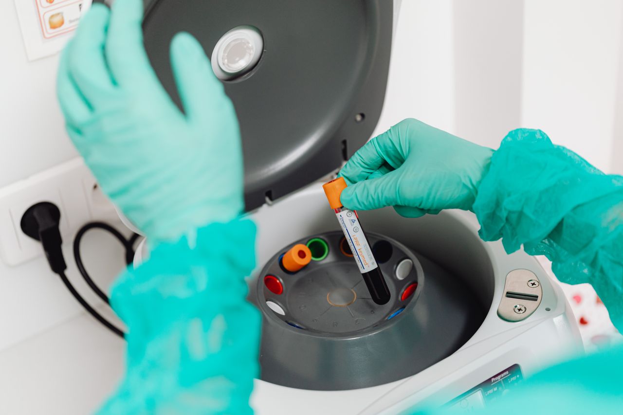 Menu A lab technician wearing gloves uses a centrifuge for blood analysis in a modern laboratory setting.