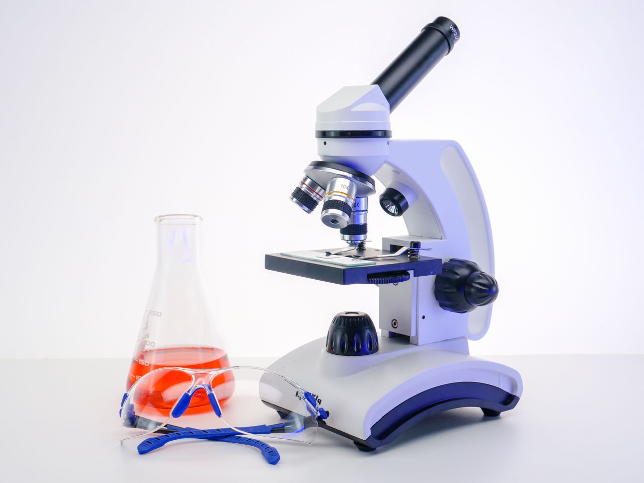 Menu Microscope and flask with red liquid in laboratory setting. Perfect for science-themed projects.