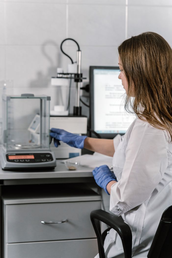 Menu Woman in lab coat and gloves conducting research with lab equipment in a laboratory setting.